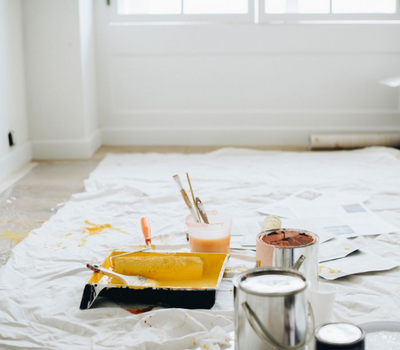 Casa preparada para pintura com chão protegido e com bandejas e latas de tinta
